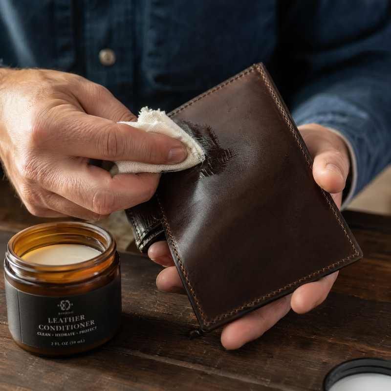Man conditioning a full-grain leather wallet with cloth and conditioner — Bull Sheath Leather