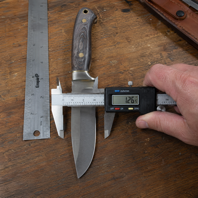 Hand measuring fixed blade knife with digital calipers showing blade width — Bull Sheath Leather