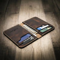 Handmade leather wallet in walnut brown color with visible stitching, branded "Bull Sheath Leather" and "Made in Texas," on a wooden surface.