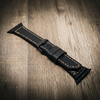 Apple Watch Leather Band in black full-grain leather with beige stitching.