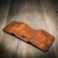 Trinity western trifold wallet in chestnut brown leather, facedown to show off the intricate stitching and a smooth finish, handmade in the USA.
