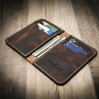 Handmade western vertical leather wallet in walnut brown color, open to show card slots and cash.