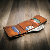 Trinity western trifold wallet in chestnut brown leather, featuring multiple card slots, a cash compartment, and a clear ID window, displayed open with cards and cash inside.
